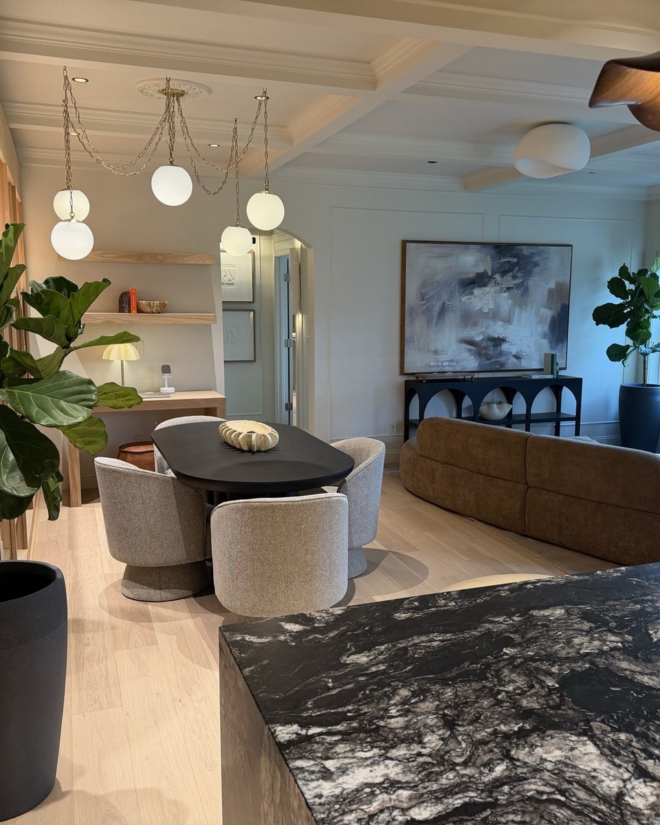 Finished interior with sculptural seating, pendant lighting, warm wood, and layered stone
