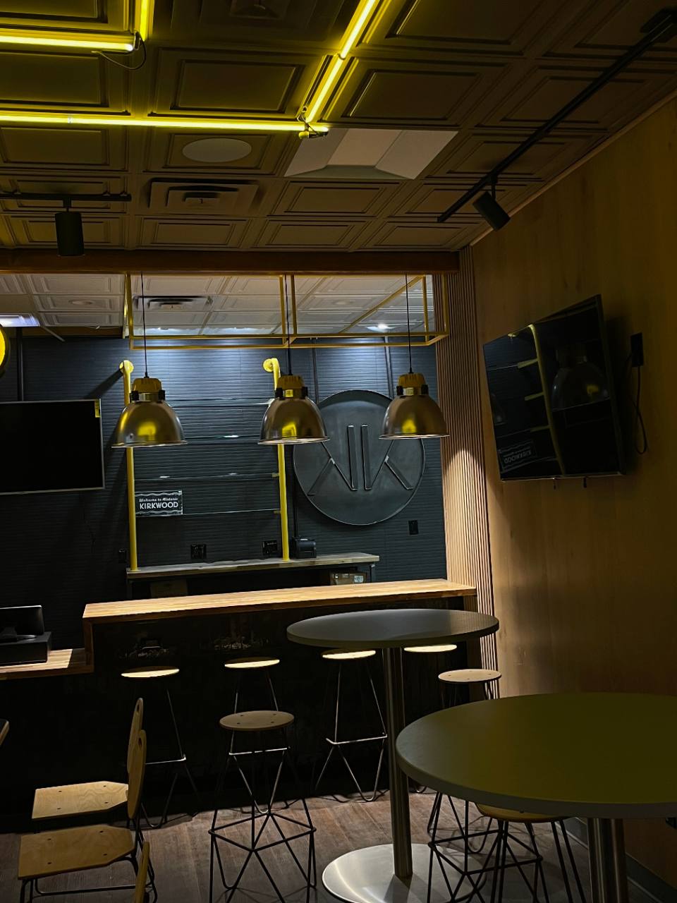 Commercial dining buildout with warm wood, black wall treatment, and yellow architectural lighting