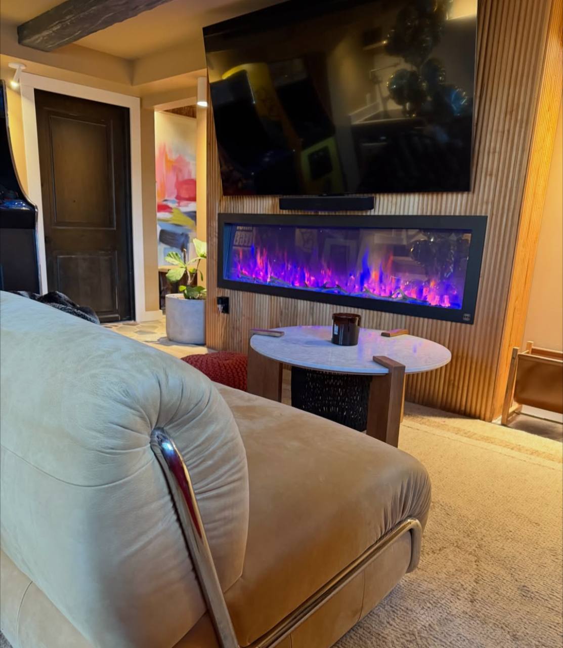 Finished lounge with fluted media wall, mounted television, and electric fireplace