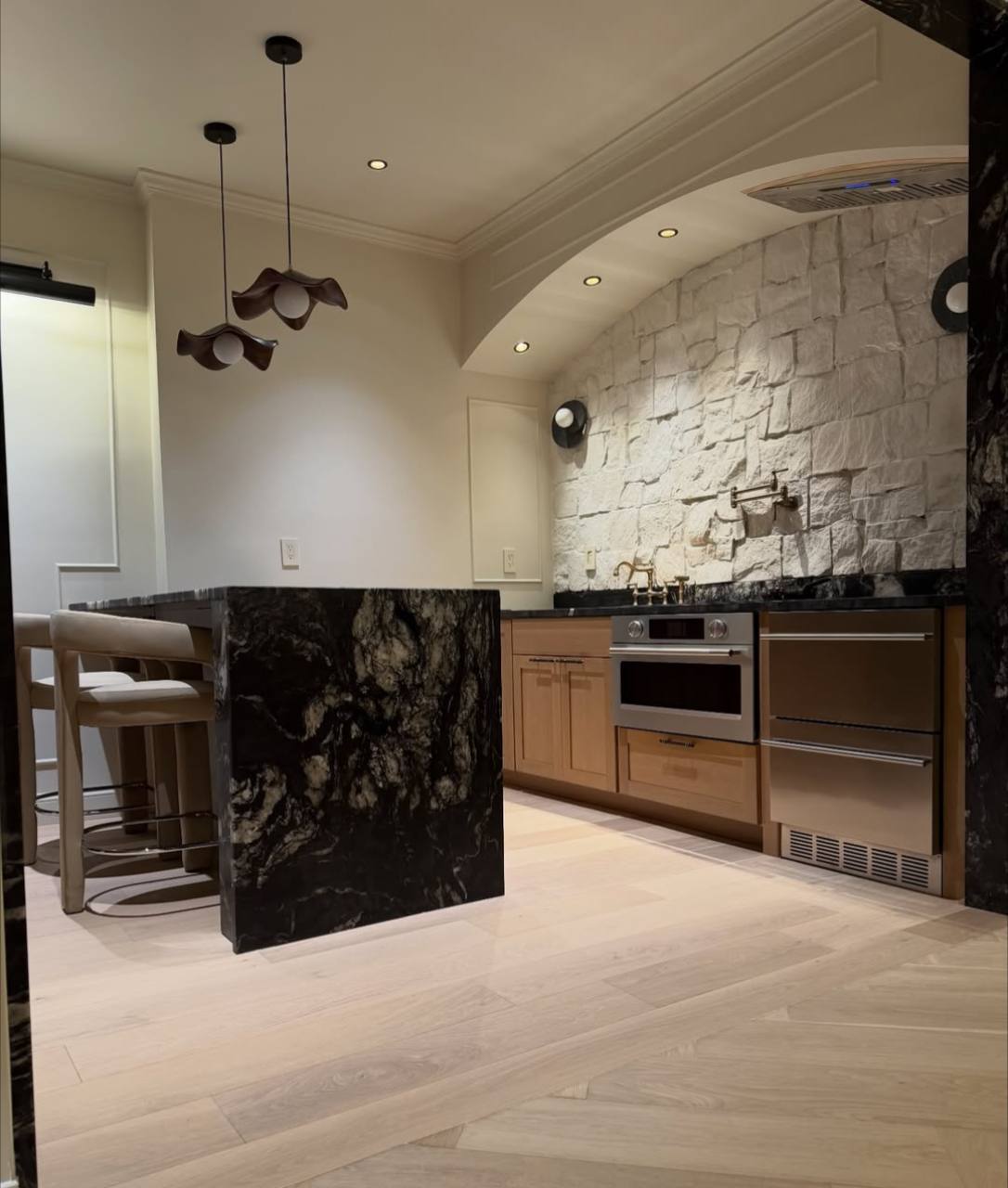 Kitchen renovation with stone backsplash, custom island, and warm cabinetry